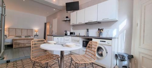 une cuisine avec une table et des chaises ainsi qu'un lave-linge dans l'établissement Little Suite - Suzanne, à Lille