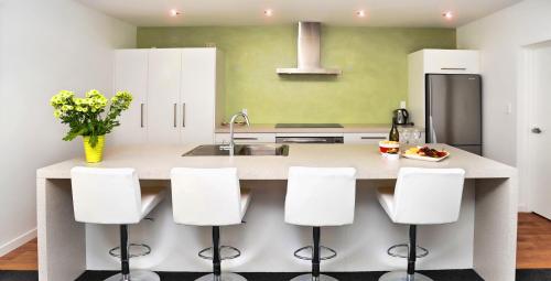 a kitchen with white cabinets and a counter with white stools at Holiday home Queen Charlotte in Anakiwa