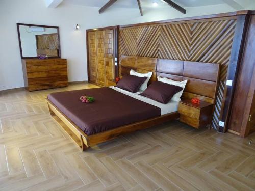 a bedroom with a large wooden bed with purple pillows at Beach Loft in Nosy Be