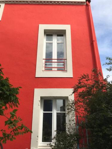 ein rotes Gebäude mit zwei Seitenfenstern in der Unterkunft Maison atypique au sein du joli village de Trentemoult in Rezé