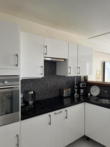 une cuisine avec des armoires blanches et des comptoirs noirs dans l'établissement Appartement à 50 mètres de la Plage des Estagnots à Seignosse, Landes, à Seignosse