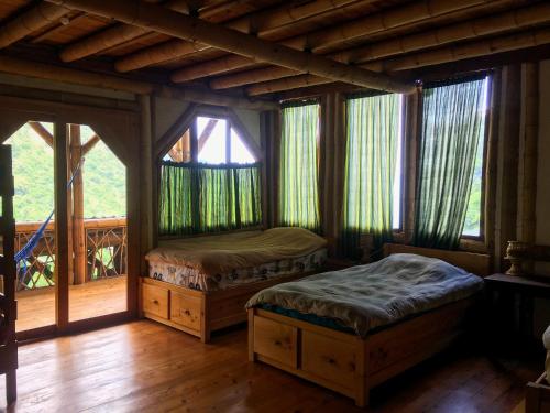 1 dormitorio con 2 camas en una habitación con ventanas en Bambu Guest House, en Tzununá