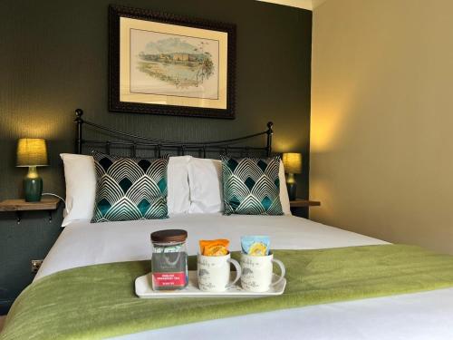 a bed with a tray of food and two cups on it at Red Lion in Bakewell