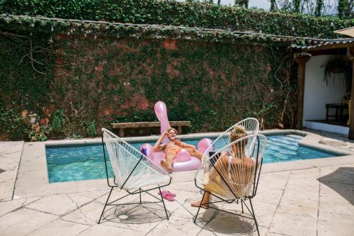 two women sitting in lawn chairs next to a swimming pool at Casi Casa in Antigua Guatemala
