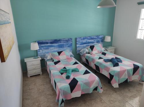 two beds in a room with blue walls at Casa de los pajaritos. in Charco del Palo