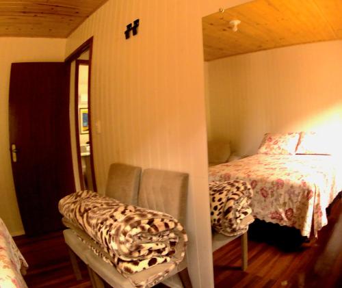 um quarto com uma cama, um espelho e cadeiras em Cabana das Montanhas em Caxias do Sul