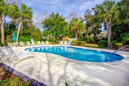 a large swimming pool with chairs and palm trees at Xanadu in Hilton Head Island
