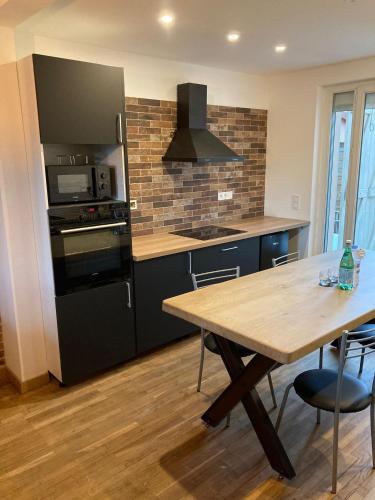 - une cuisine avec une table en bois et un réfrigérateur noir dans l'établissement Villa Sagrada l'Atelier ****, à Toulouse