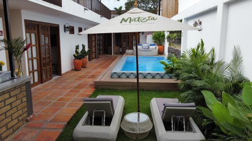 a patio with an umbrella and chairs and a pool at Matisia Hotel Boutique in Guaduas