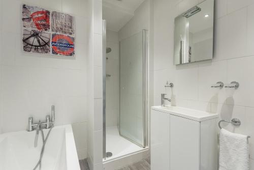 La salle de bains blanche est pourvue d'une douche et d'un lavabo. dans l'établissement Paddington/Lancaster Gate Luxury Apartment by Hyde Park, à Londres