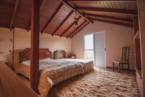 a bedroom with a bed and a large window at Casa Fuchsia Régia em Rancho Queimado/SC in Rancho Queimado