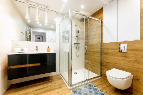 une salle de bain avec une douche en verre et des toilettes dans l'établissement Apartament 21B Niebieskie Apartamenty z basenem krytym, odkrytym, salą zabaw, animacjami, à Poddąbie