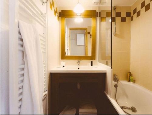 a bathroom with a sink and a mirror and a tub at Cosy Val Tho ski aux pieds in Val Thorens