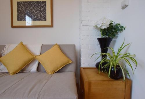 a couch with two pillows and a vase of flowers at Modern Apartment In The Centre of Teignmouth in Teignmouth