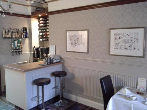 a bar in a restaurant with a table and stools at Arundel House in Whitby
