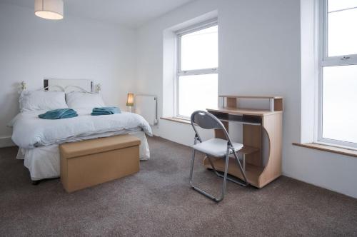 a bedroom with a bed and a desk and a chair at Ty Golau - 3 Bed Holiday Home - Pembroke in Pembroke