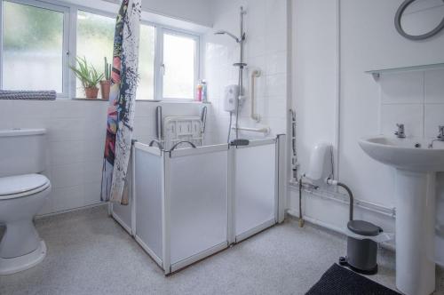La salle de bains blanche est pourvue de toilettes et d'un lavabo. dans l'établissement Ty Golau - 3 Bed Holiday Home - Pembroke, à Pembroke