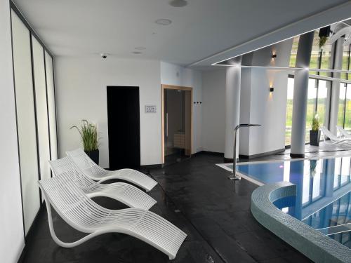 eine Lobby mit zwei weißen Stühlen und einem Pool in der Unterkunft Apartament w Westin House Resort Kołobrzeg in Kołobrzeg