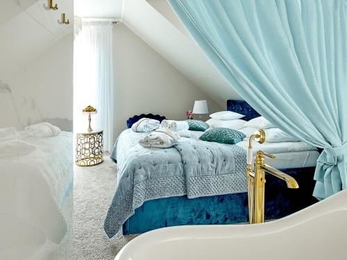 a bedroom with a bed with a blue blanket and a tub at La Rose Residence in Mikołajki