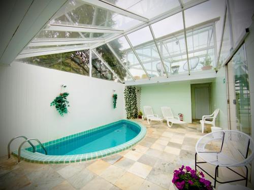 una piscina en una habitación con techo de cristal en Pousada Parque das Flores, en Campos do Jordão