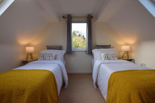 2 Einzelbetten in einem Zimmer mit Fenster in der Unterkunft St Keyne - A Hidden Gem Nestled in Shaldon in Shaldon
