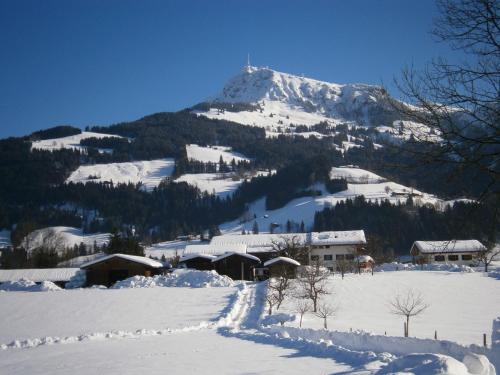 a snow covered mountain with a house in the foreground at Filzenhof in Kitzbühel