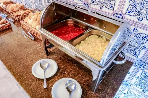 a counter with bowls and spoons on a table with food at Cannes Palace Hotel in Vitória