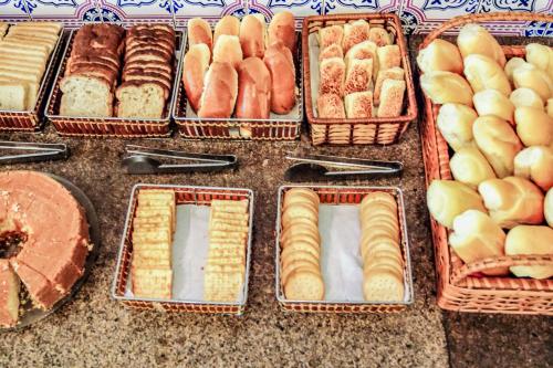a bunch of trays of different types of bread and pastries at Cannes Palace Hotel in Vitória