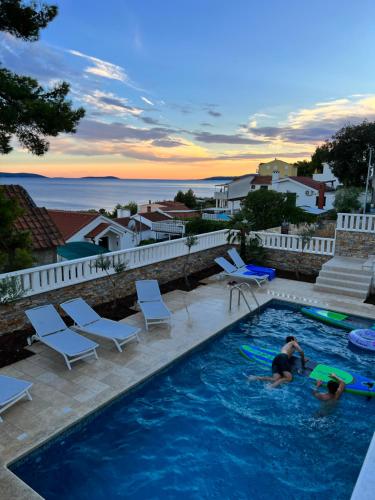 2 Personen in einem Pool mit Meerblick in der Unterkunft Luxury Beachfront Villa Carlisa in Ciovo