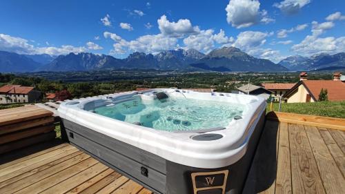 a hot tub on a deck with mountains in the background at Casa dei Moch in Belluno