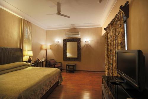 a bedroom with a bed and a flat screen tv at Ajit Bhawan - A Palace Resort in Jodhpur
