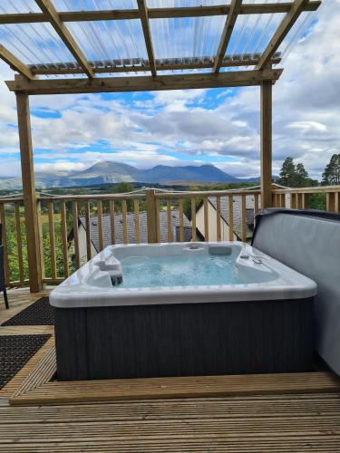 a hot tub on a deck with a pergola at Nadurra But and Ben - Where the Ordinary Becomes Extraordinary in Fort William