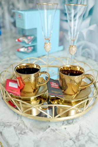 two gold coffee cups on a gold tray on a table at La Rose Residence in Mikołajki