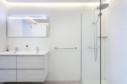 a white bathroom with a shower and a sink at Deluxe Apartment in Costa Adeje in Adeje