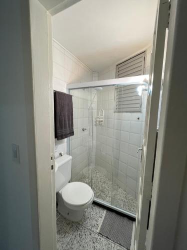 a bathroom with a toilet and a glass shower at KITNET ACONCHEGANTE A 3 MINUTOS DA PRAIA in Guarapari
