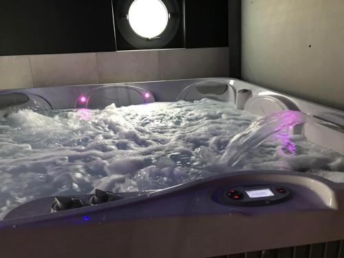 a jacuzzi tub filled with snow and purple lights at Gîte spa sauna piscine in Aubin-Saint-Vaast