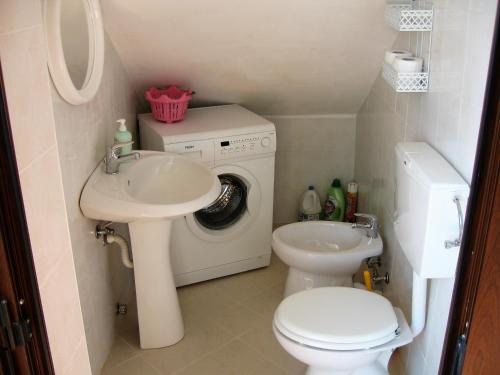 a bathroom with a sink and a toilet and a washing machine at Casa Maria Russo in Casal Velino
