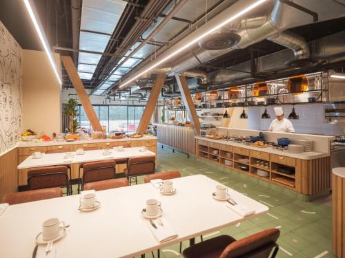 a restaurant with tables and a chef in the kitchen at Novotel Mexico City World Trade Center in Mexico City