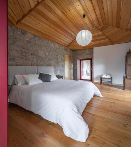 a bedroom with a large white bed with a wooden ceiling at Casa da Moiroa in Sendim