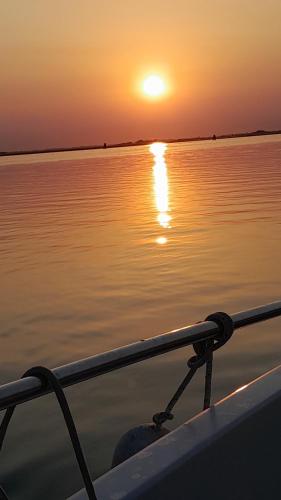 a boat with the sun setting on the water at La Bricola in Cavallino-Treporti