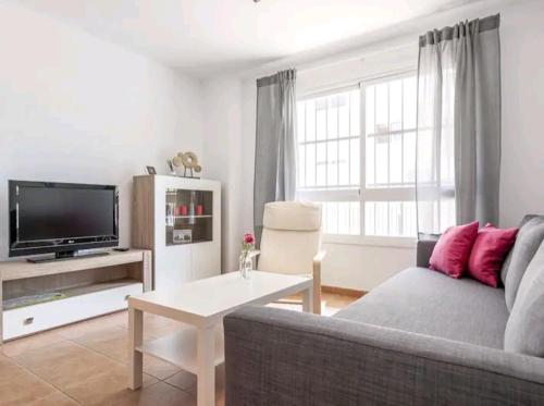 a living room with a couch and a tv at Apartamento con patio y piscina cerca de Sevilla in La Algaba