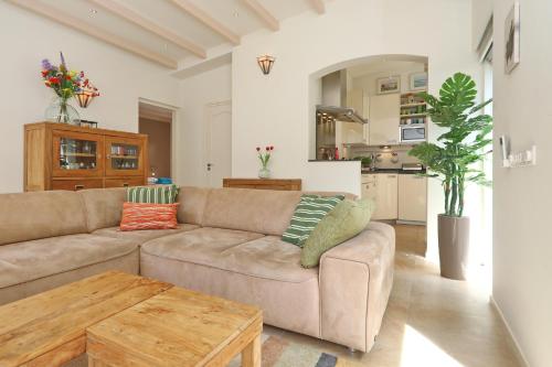 a living room with a couch and a table at Sunnybeachhouse aan het bos, tussen zee en meer. in Noordwijkerhout