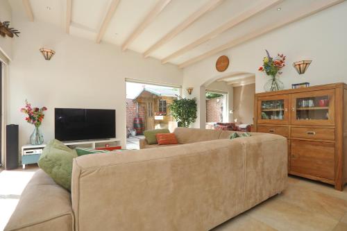 a living room with a couch and a tv at Sunnybeachhouse aan het bos, tussen zee en meer. in Noordwijkerhout