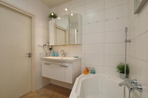 een badkamer met een bad, een wastafel en een spiegel bij Sunnybeachhouse aan het bos, tussen zee en meer. in Noordwijkerhout