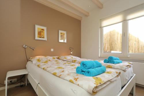 Un dormitorio con una cama con toallas azules. en Sunnybeachhouse aan het bos, tussen zee en meer., en Noordwijkerhout