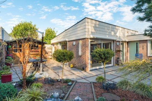 a brick house with a patio in the yard at Sunnybeachhouse aan het bos, tussen zee en meer. in Noordwijkerhout