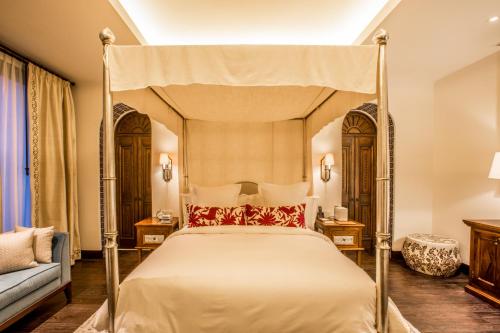 a bedroom with a four poster bed and a couch at Banyan Tree Puebla in Puebla