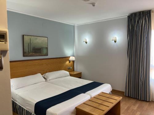 ein Hotelzimmer mit einem Bett und einem Tisch in der Unterkunft Alojamientos Cervantes in Linares