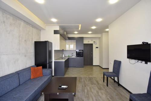 a living room with a blue couch and a kitchen at Rent Inn Yerevan on Koghbaci Street in Yerevan