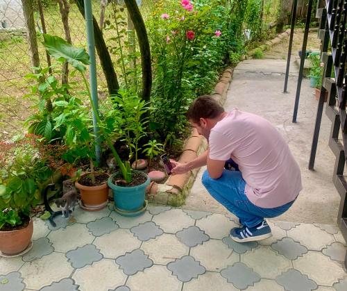 a man squatting down next to some plants at Butichi Guest House in Chiatʼura